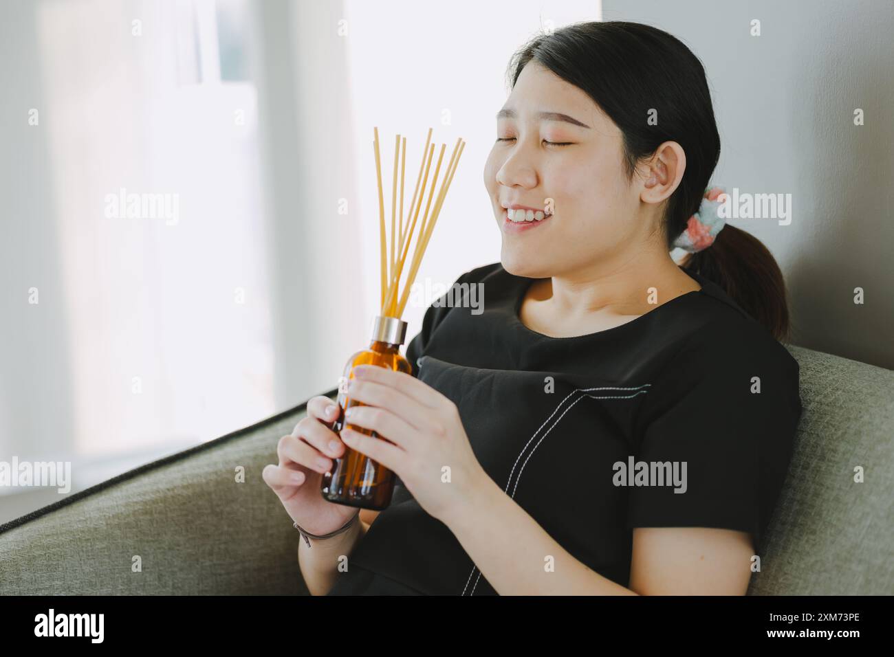 Frau glücklich mit Öl Aroma Sticks Heim Luft Auffrischung Duft Diffusor guter Geruch Raum Parfüm Relax Lächeln Stockfoto