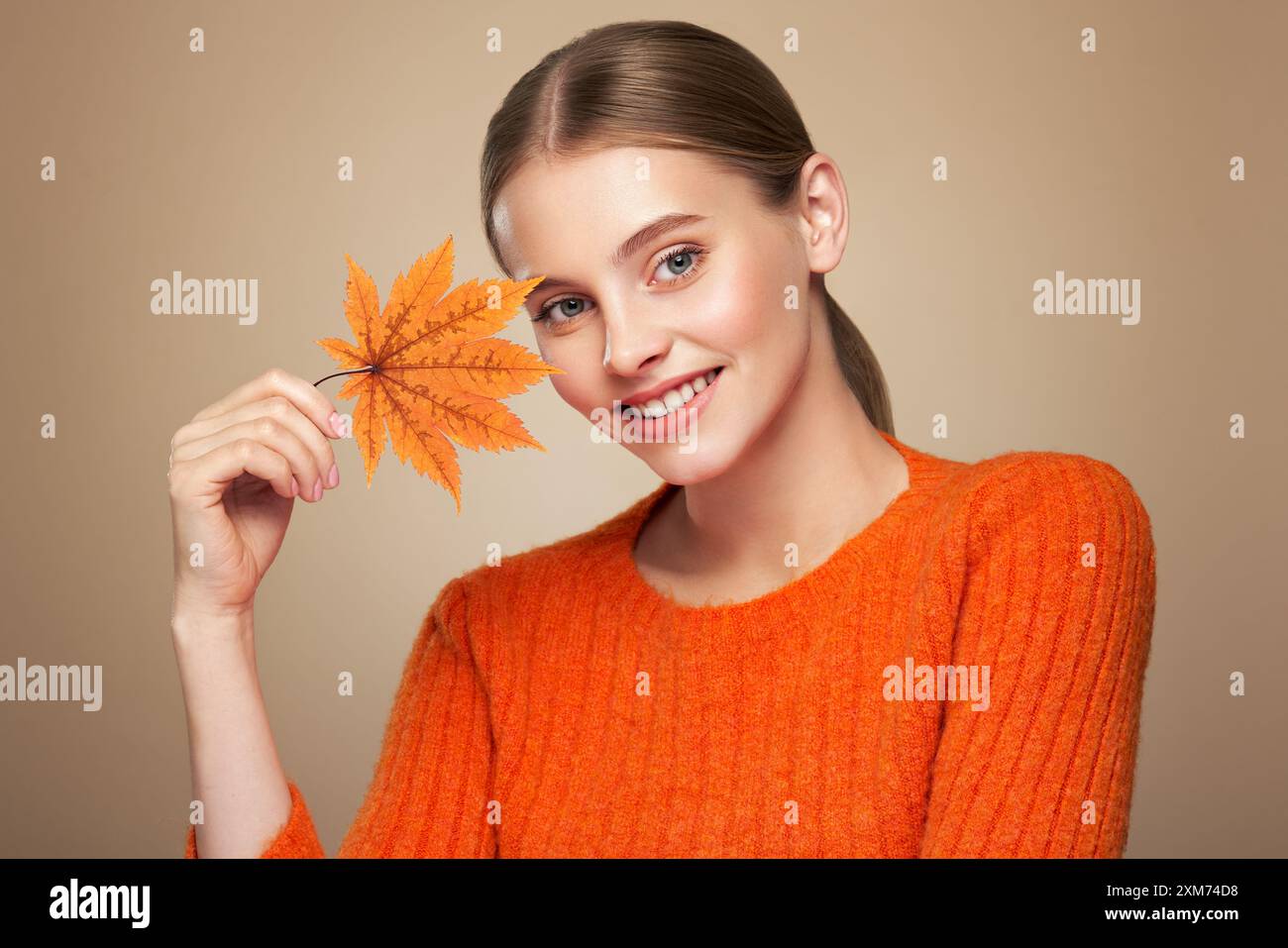 Porträt der schönen jungen Frau in orangener Bluse mit Herbstblättern. Gesunde saubere frische Haut natürliche Make Up Schönheit Augen Stockfoto