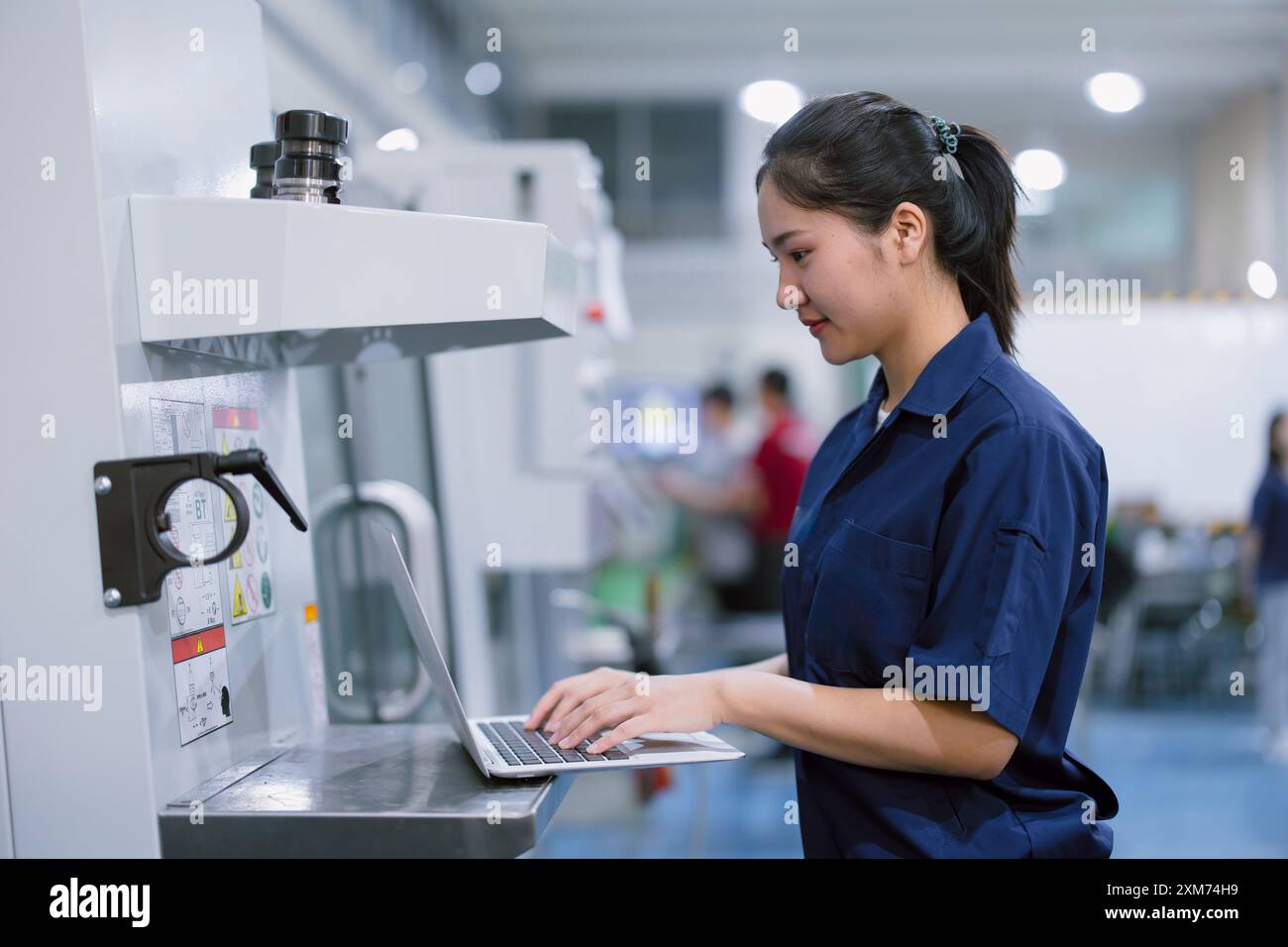 Asiatische Arbeiterinnen arbeiten in der Schwerindustrie mit CNC-Drehmaschine Fräsen Metallmaschine in Stahlproduktfabrik Stockfoto