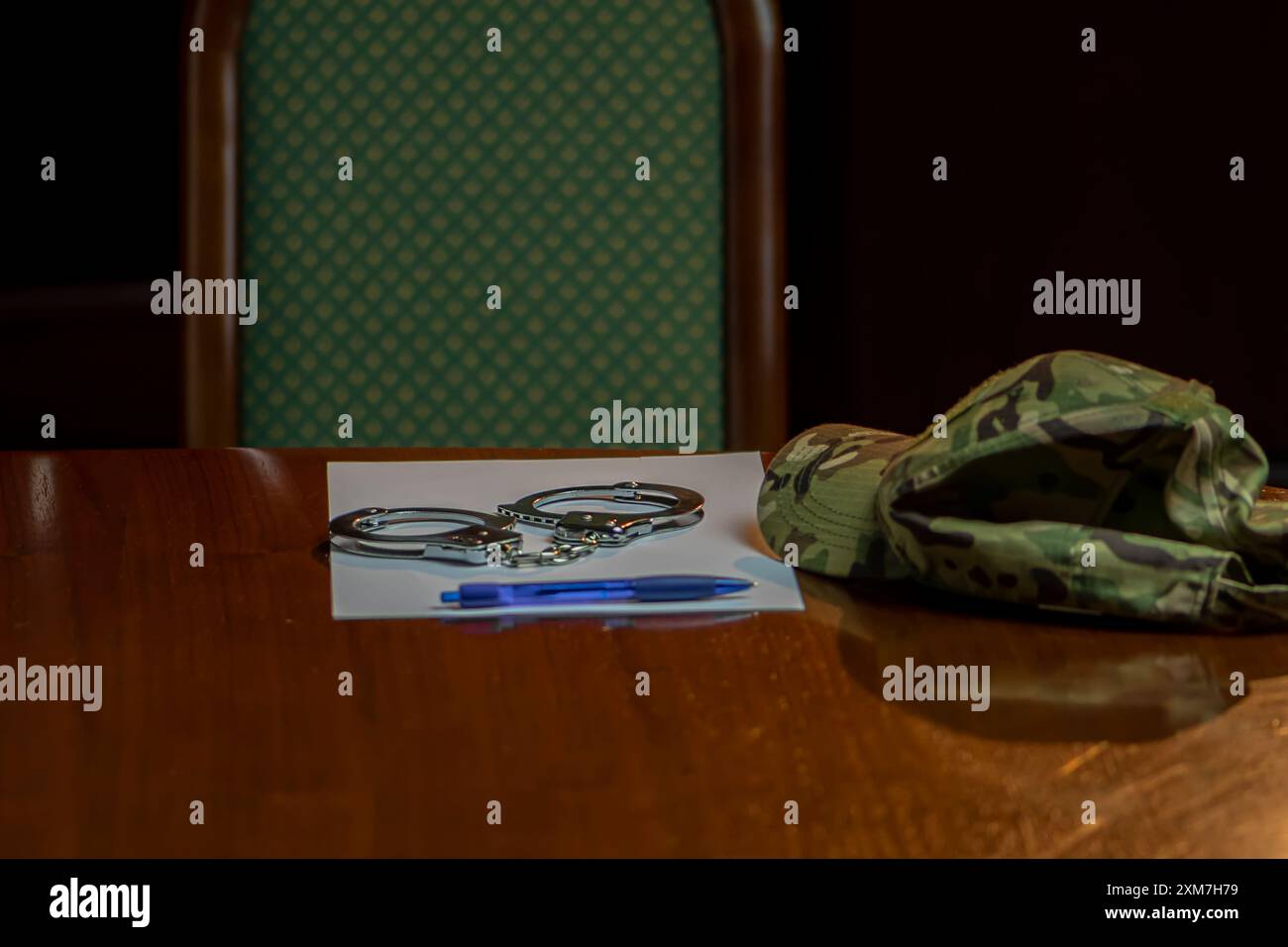 Auf einem Holztisch lagen eine Tarnkappe, ein Paar Militärmedaillons, Metallhandschellen und ein blauer Stift mit einem Stück Papier. Stockfoto