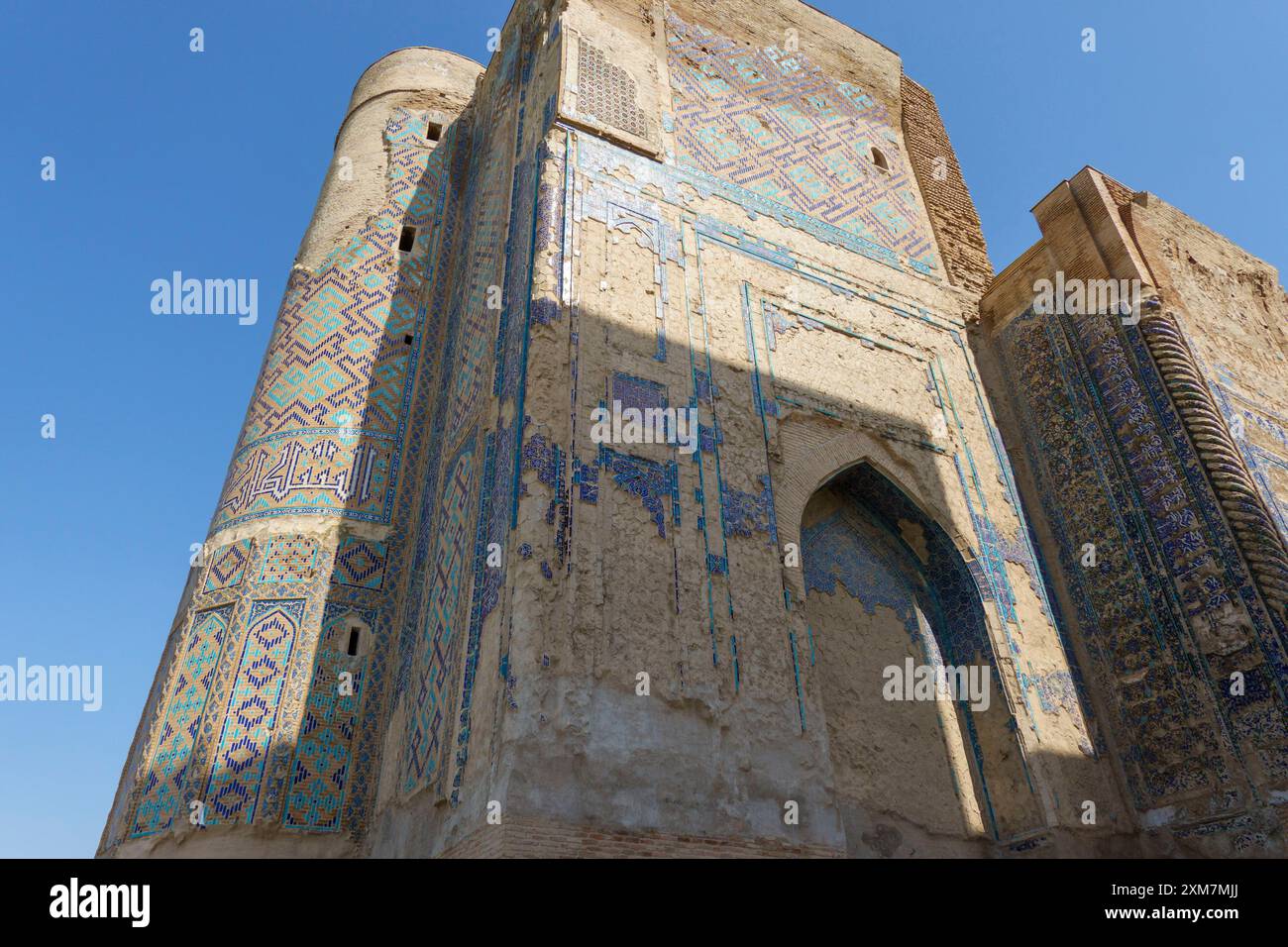 Antike islamische Architektur mit verwitterten Mosaiken und komplizierten Fliesen in einem historischen Gebäude unter einem klaren blauen Himmel in Samarkand, Usbekistan Stockfoto