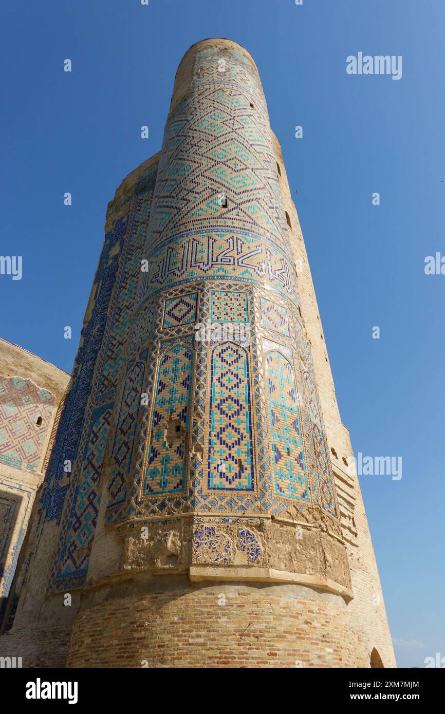 Antike türkisfarbene Mosaikturm mit islamischer Kalligraphie und komplizierten Keramikfliesen unter einem klaren blauen Himmel in Samarkand, Usbekistan Stockfoto