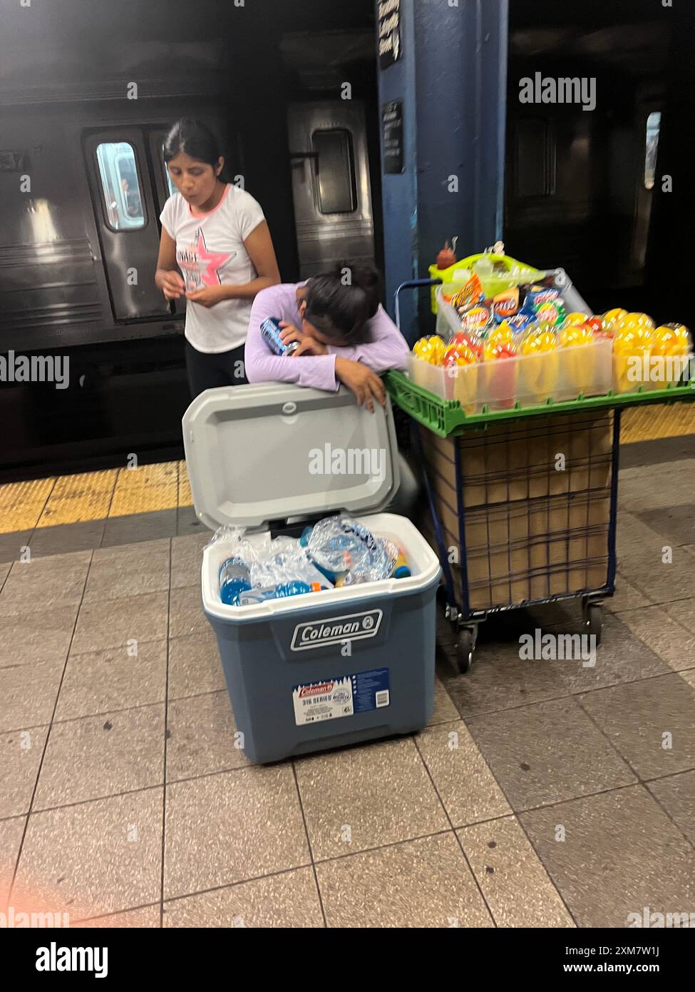 Müde Frau verkauft Obst und Wasser auf dem Bahnsteig an einer U-Bahn-Station in Manhattan, New York City. Stockfoto