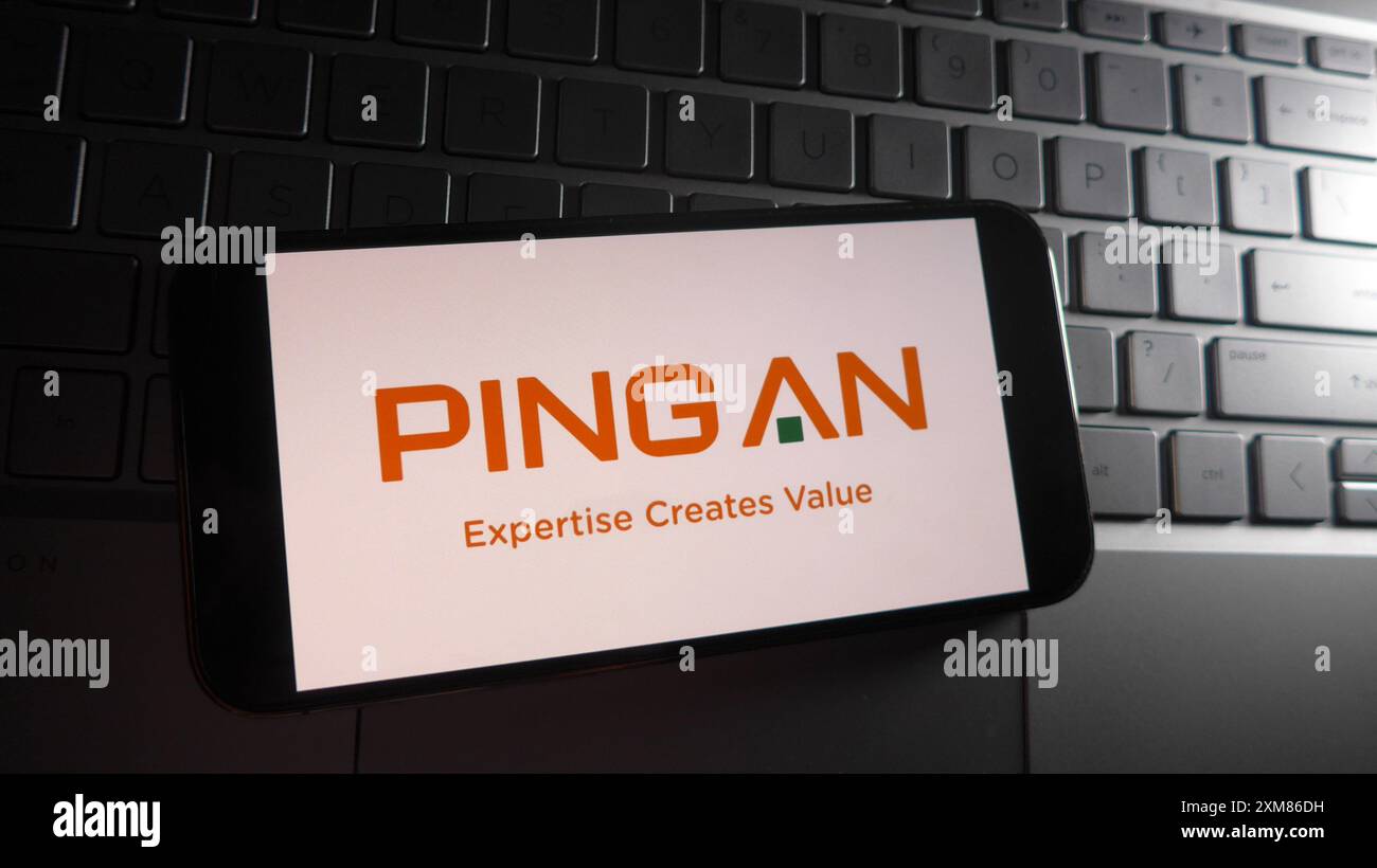 In dieser Abbildung wird das Logo „Ping an Insurance“ auf einem Smartphone mit einer Laptop-Tastatur im Hintergrund angezeigt. Stockfoto