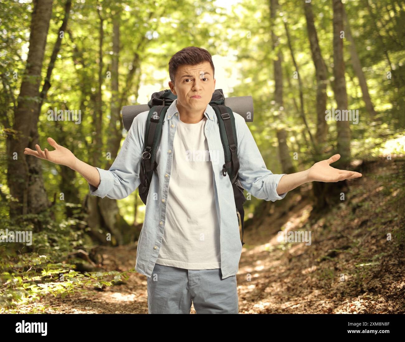 Verlorener junger männlicher Rucksackfahrer, der mit Händen im Wald gestickt hat Stockfoto