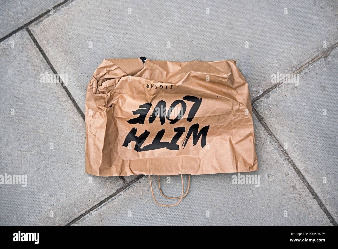 Entsorgte braune Papiertragetasche mit den Worten „With love“ auf dem Bürgersteig in Edinburgh, Schottland, Großbritannien. Stockfoto