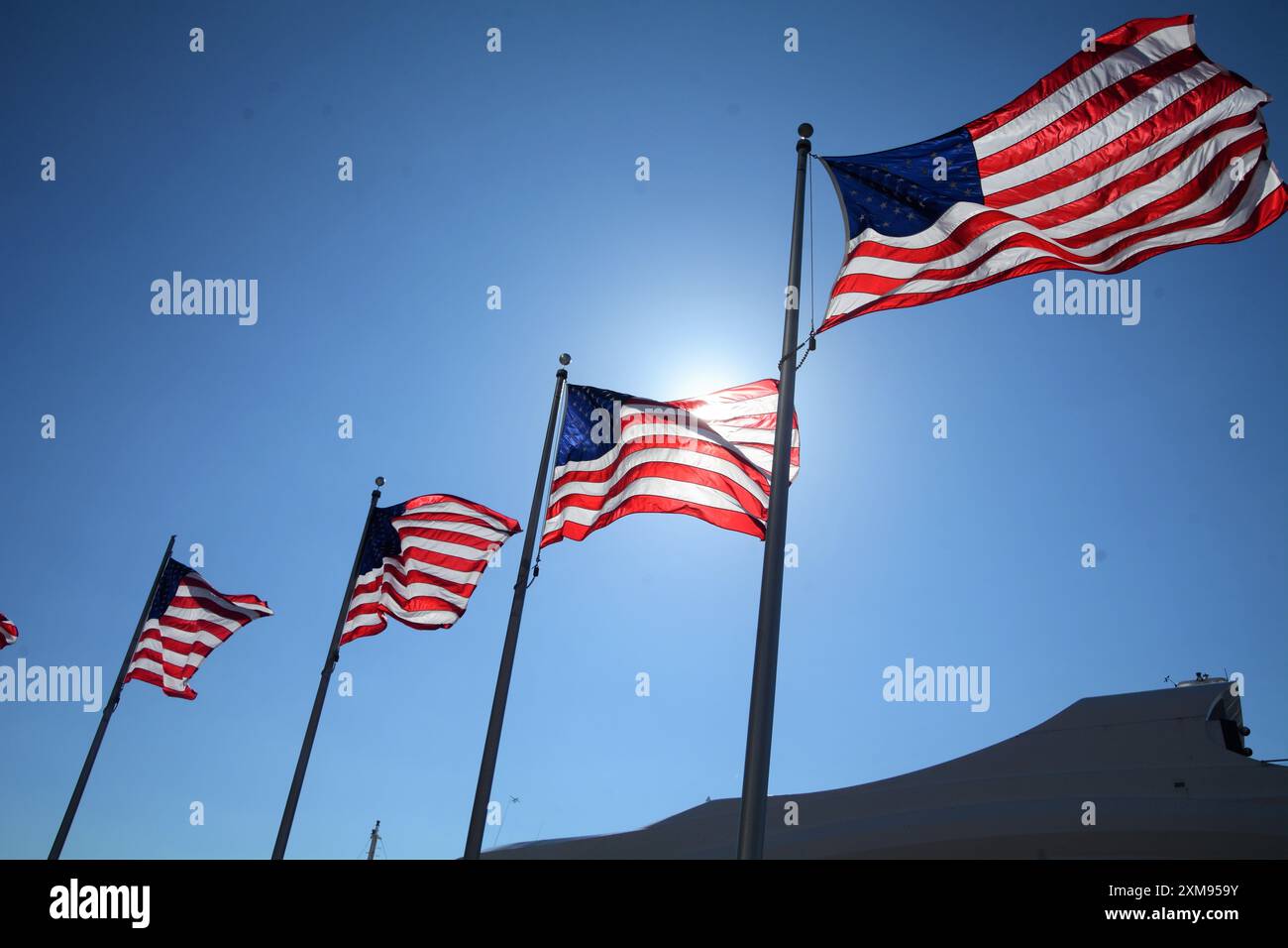 Vier amerikanische Fahnen fliegen an einem warmen Sommertag gegen einen strahlend blauen Himmel. Stockfoto