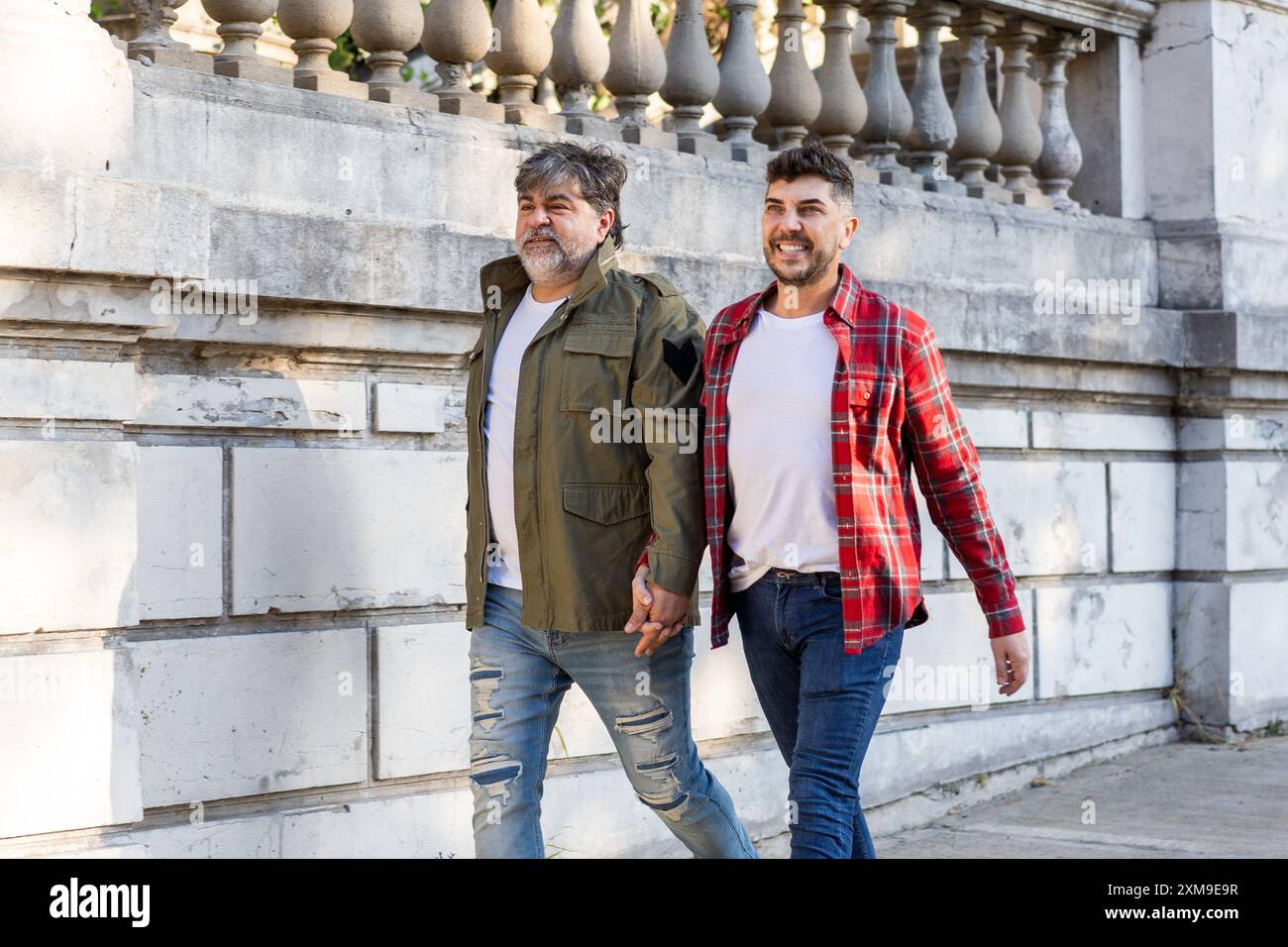 Zwei anhänglich schwule Männer, die auf der Straße laufen, während sie Hände halten Stockfoto