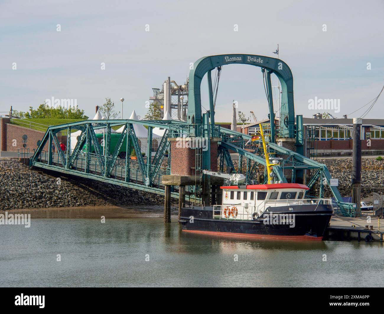 Eine grüne Brücke mit einem rot-weißen Boot im Hafen unten und Blick auf das Wasser, wilhelmshaven, deutschland Stockfoto