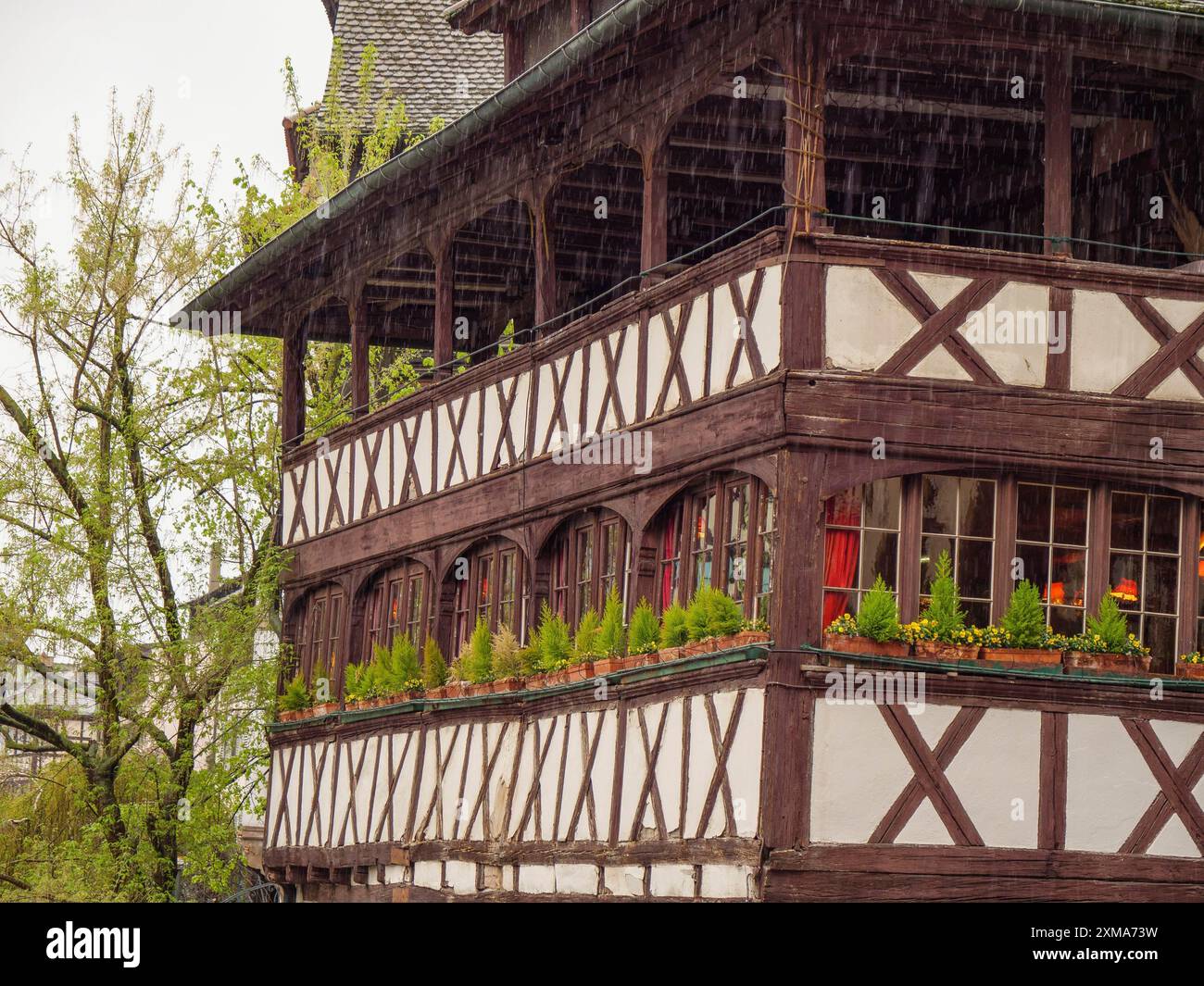 Ein großes Fachwerkhaus mit einem bepflanzten Balkon, aufgenommen an einem regnerischen Tag, straßburg, frankreich Stockfoto