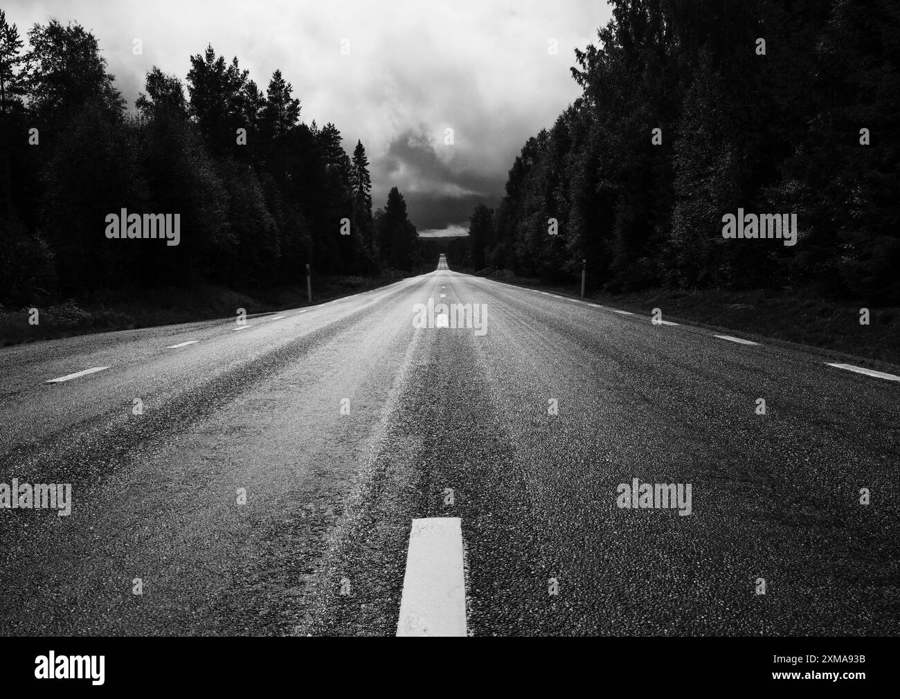 Nasse Landstraße mit regnerischem Himmel, schwarz-weiß, Vaermland, Schweden Stockfoto