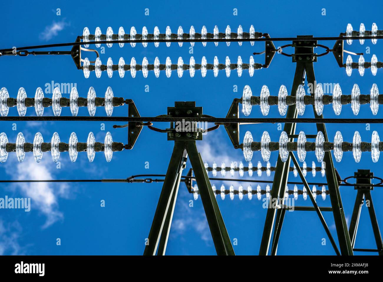 Isolatoren aus Glas an einer Hochspannungsleitung hängen sie als Aufhängevorrichtung zwischen dem Pylon und dem stromführenden, nicht isolierten Kabel an den Pylonen Stockfoto