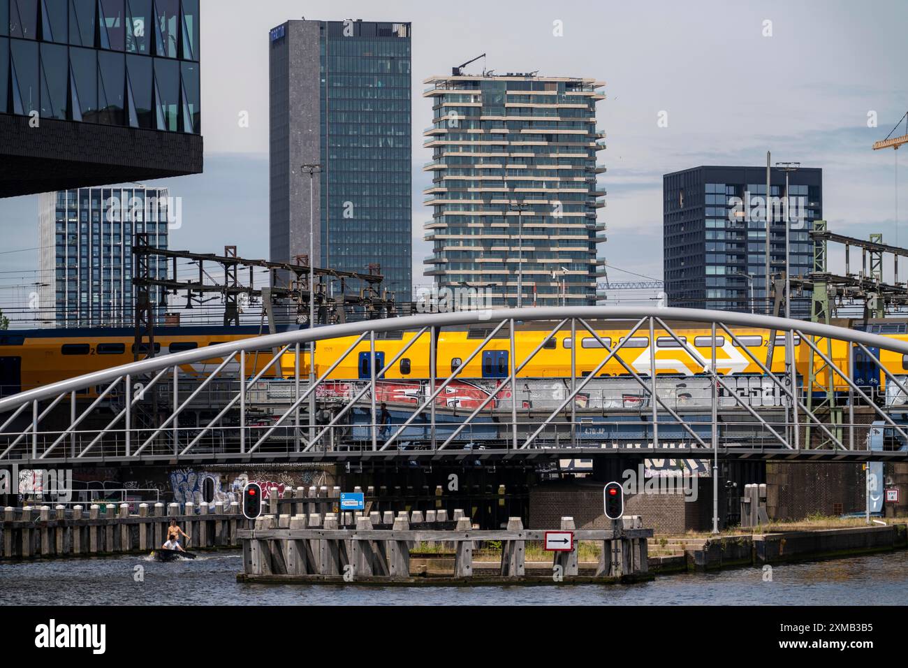 Die Eisenbahnbrücke, die direkt am Bahnhof Amsterdam Centraal liegt, überquert den Kanal vom Fluss Ij zum Oosterdok Hafenbecken, Intercity-Zug Stockfoto