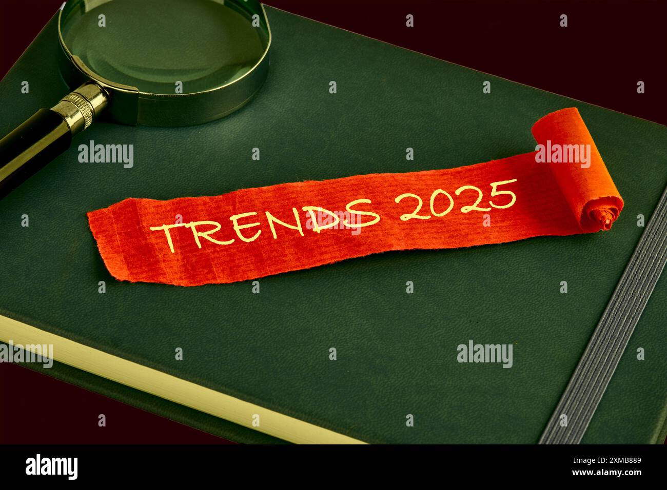Symbol für konzeptionelle Trends 2025. Kopierbereich. Trends 2025 Wörter auf einem roten Blatt Papier, die auf einem grünen Geschäftsbuch liegen Stockfoto
