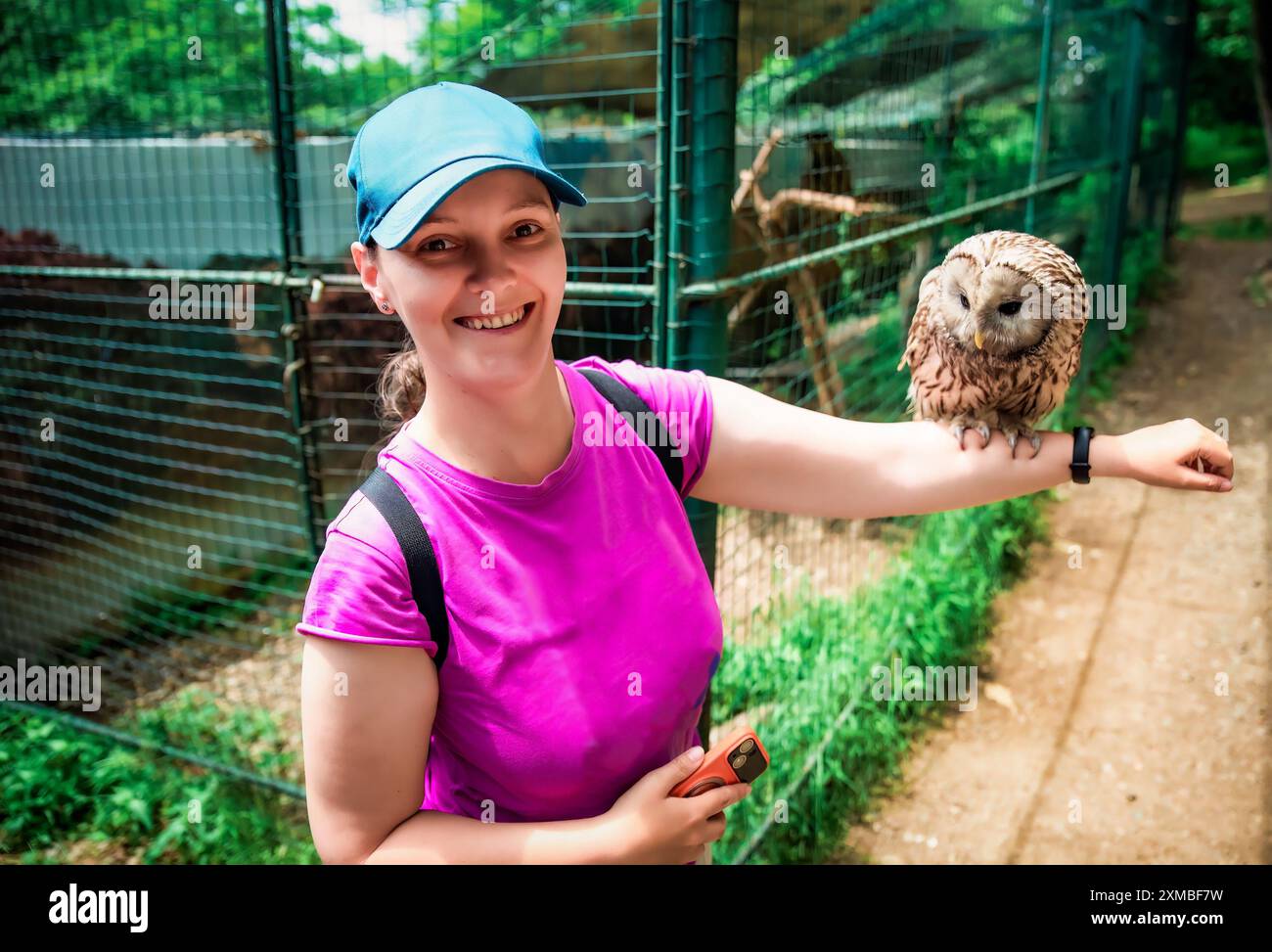 Porträt einer lachenden 36-jährigen russischen Frau mit Ural-Eulen (Strix uralensis) auf dem Arm sitzendem Vogel Stockfoto