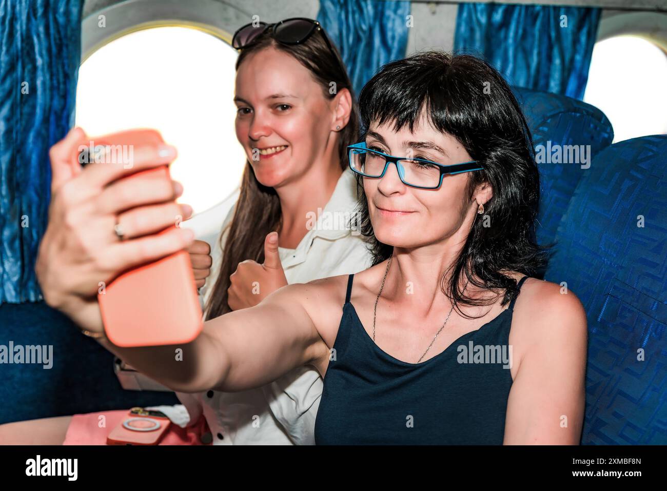 Zwei schöne Frauen, die ein Selfie machen, sitzen in der Flugzeugkabine Stockfoto