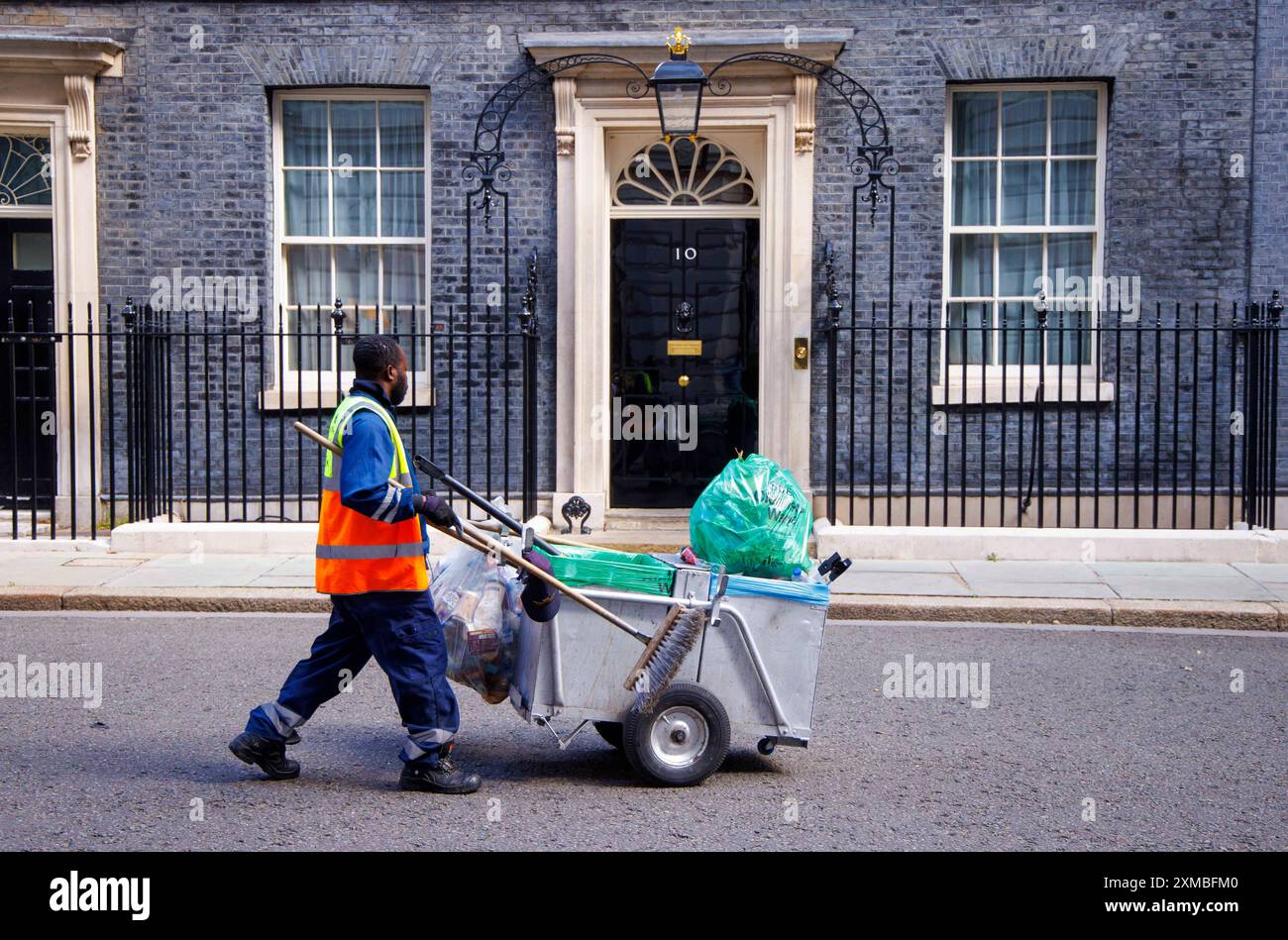 Ein Müllsammler geht an der Tür der Downing Street 10 vorbei. Das Haus des neuen Premierministers, Sir Keir Starmer. Stockfoto