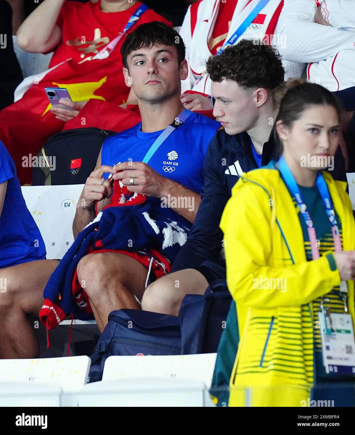 Der britische Tom Daley strickt, während er am ersten Tag der Olympischen Spiele in Paris 2024 in Frankreich das 3-m-Springboard-Finale der Frauen im Aquatics Centre ansieht. Bilddatum: Samstag, 27. Juli 2024. Stockfoto