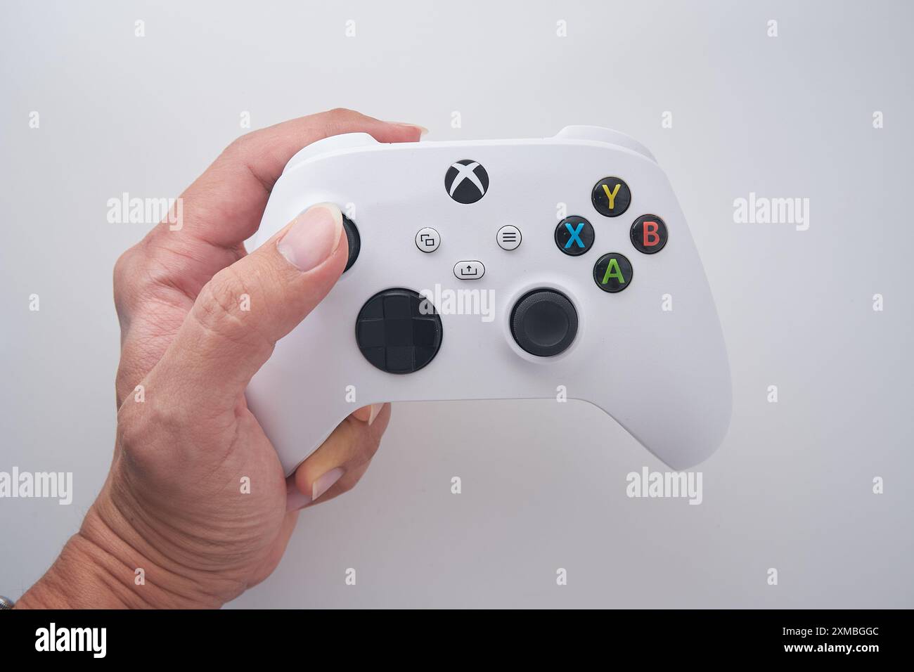 Ein Mann hält einen XBOX-Controller mit weißem Hintergrund. Stockfoto