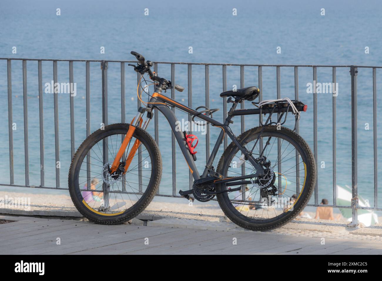 Das Fahrrad lehnt sich an einen Zaun und das blaue Meer Stockfoto