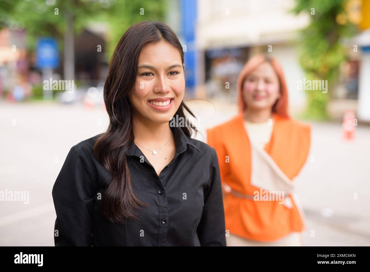 Ehrliches Porträt von zwei schönen asiatischen Frauen, die draußen lächeln Stockfoto