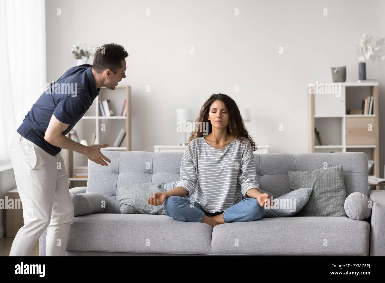 Der Mann schreit die Frau an, während sie Yoga macht Stockfoto