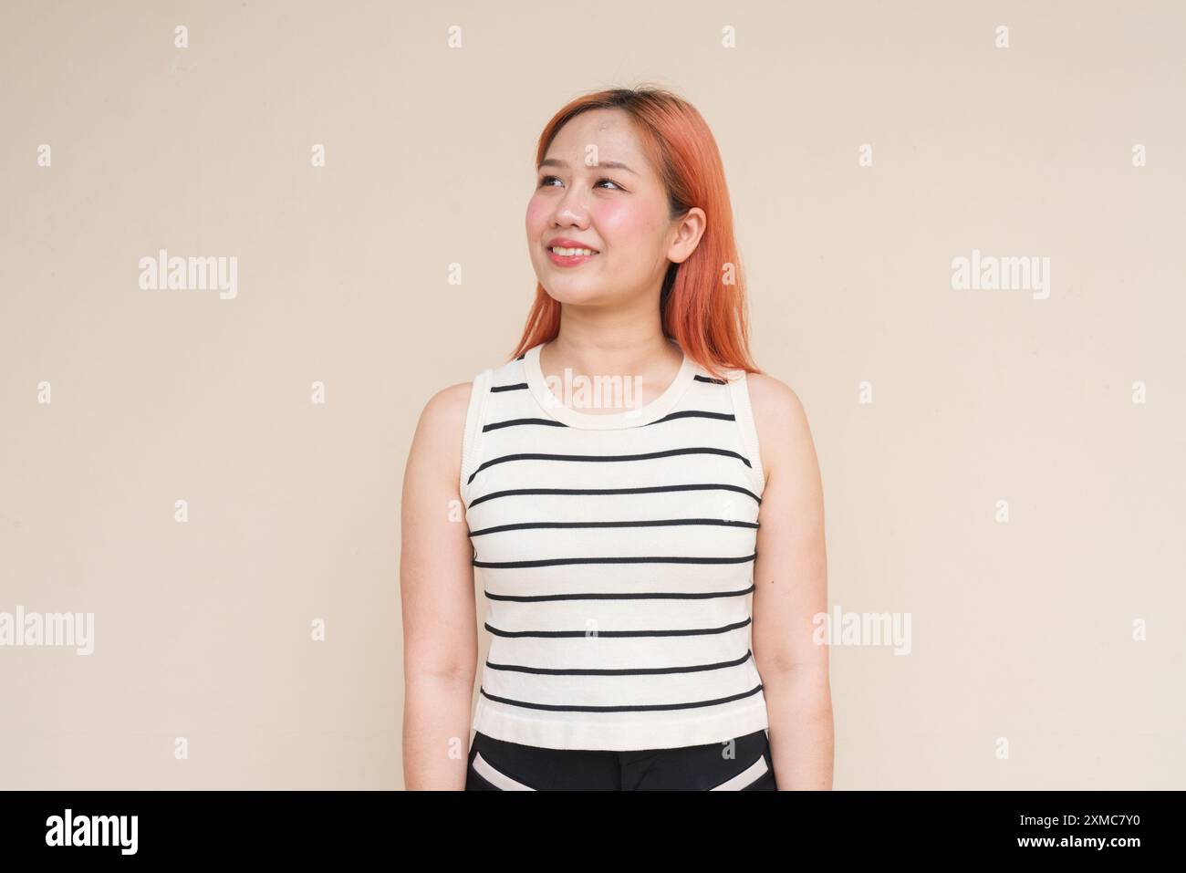 Porträt einer glücklichen asiatischen Frau, die vor dem Hintergrund von Plain Studio denkt Stockfoto