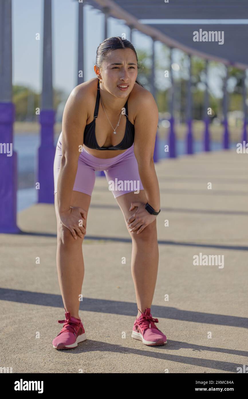 Müde Latina-Läuferin, die sich nach dem Laufen ausgeruht hat. Stockfoto