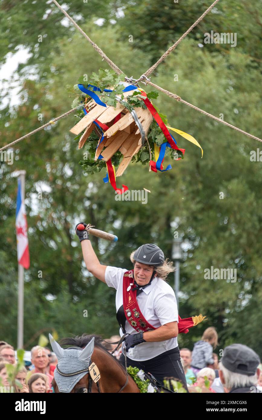 Klockenhagen, Deutschland. Juli 2024. Eine Pferdefrau schlägt eine Heringsboje mit einem Schläger. Sie konkurriert mit 15 weiteren Fahrern um mehrere Königstitel beim traditionellen Fassschlagen in Klockenhagen. 2017 wurde die weit verbreitete Praxis des Fass-Schlagens auf der Ostsee in die Liste des immateriellen Kulturerbes der UNESCO aufgenommen. Quelle: Stephan Schulz/dpa/Alamy Live News Stockfoto