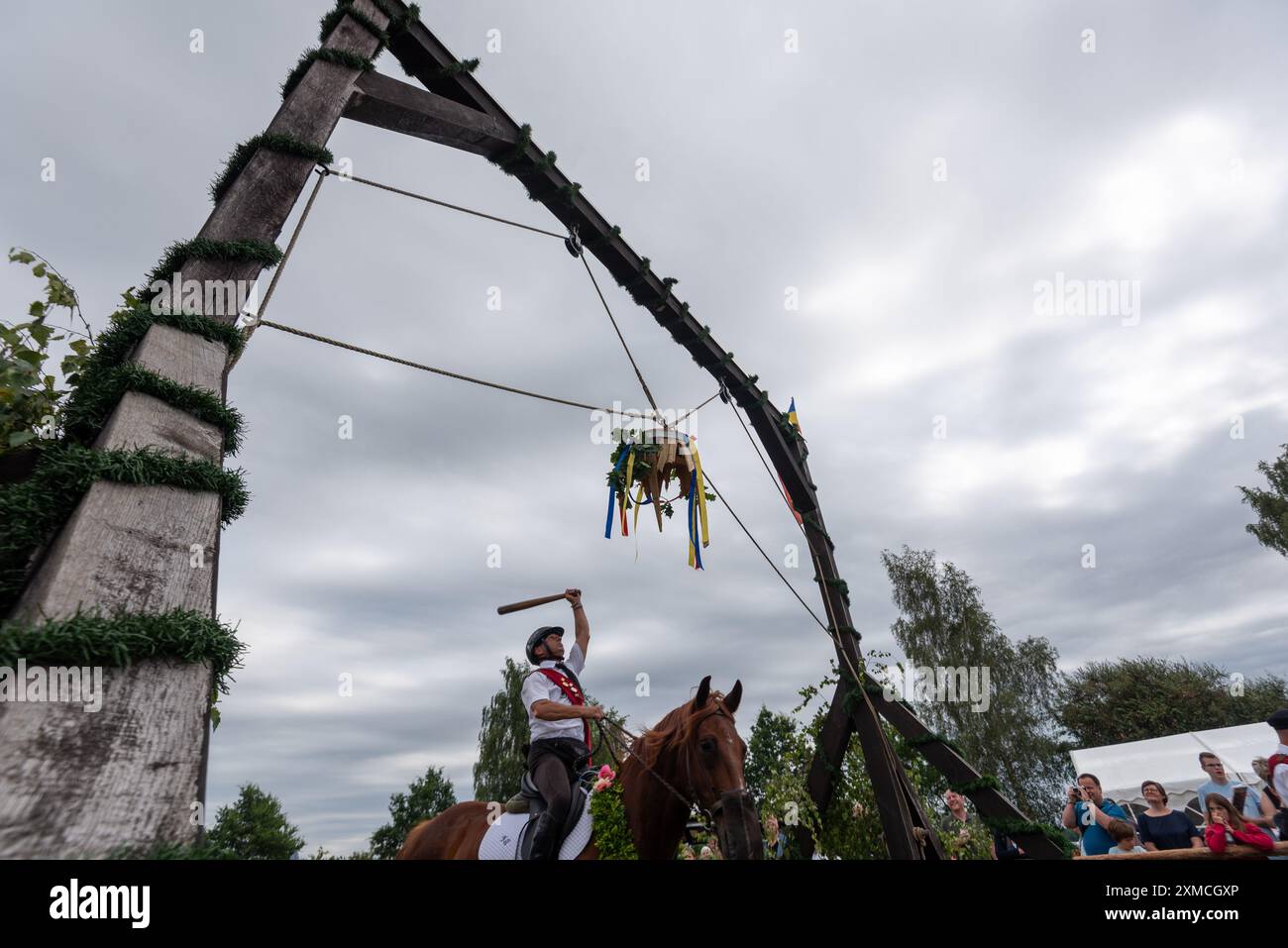 Klockenhagen, Deutschland. Juli 2024. Ein Reiter schlägt eine Heringsboje mit einem Schläger. Er konkurriert mit 15 weiteren Fahrern um mehrere Königstitel beim traditionellen Fassschlagen in Klockenhagen. 2017 wurde die weit verbreitete Praxis des Fass-Schlagens auf der Ostsee in die Liste des immateriellen Kulturerbes der UNESCO aufgenommen. Quelle: Stephan Schulz/dpa/Alamy Live News Stockfoto