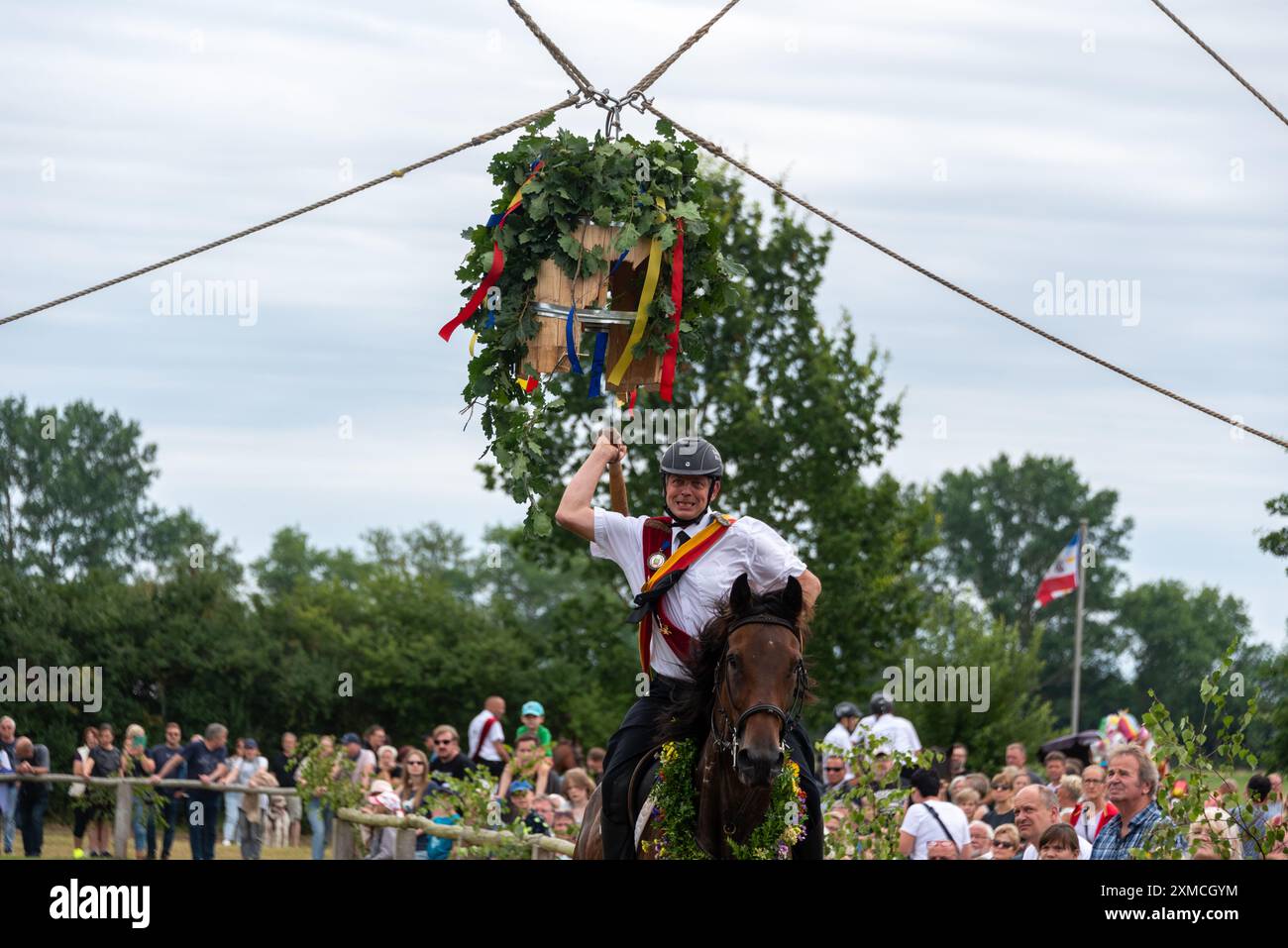 Klockenhagen, Deutschland. Juli 2024. Ein Reiter schlägt eine Heringsboje mit einem Schläger. Er konkurriert mit 15 weiteren Fahrern um mehrere Königstitel beim traditionellen Fassschlagen in Klockenhagen. 2017 wurde die weit verbreitete Praxis des Fass-Schlagens auf der Ostsee in die Liste des immateriellen Kulturerbes der UNESCO aufgenommen. Quelle: Stephan Schulz/dpa/Alamy Live News Stockfoto