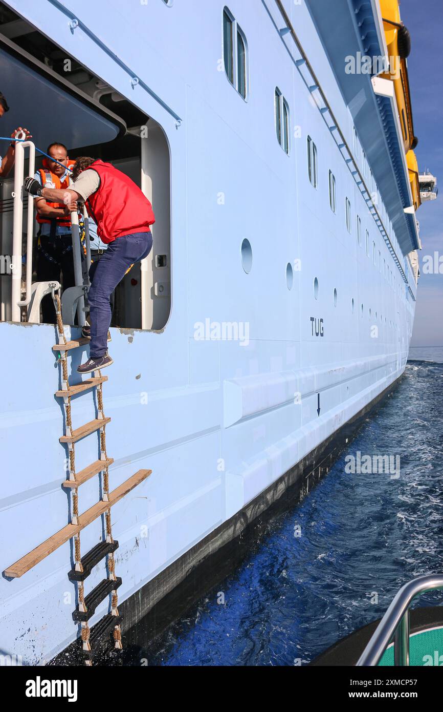 Nizza, Frankreich: Hafenpilotenboot nähert sich der riesigen MEERESHYMNE der Royal Caribbean, um in Villefranche sur Mer von Bord zu gehen. Ein einzigartiger Zwischenstopp für das größte Kreuzfahrtschiff dieses Jahr im kleinen Hafen der französischen Riviera. Nach der Sommersaison sollte das beeindruckende Schiff im Rahmen einer Umschichtung von Europa nach Singapur durch den Suez-Kanal segeln, aber nach Spannungen am Roten Meer und Drohungen mit Houthi-Raketen auf Schiffe, stattdessen wird sie ohne Passagier die Südspitze Afrikas erkunden, um Dubai und Asien zu erreichen. Quelle: Kevin Izorce/Alamy Live News Stockfoto