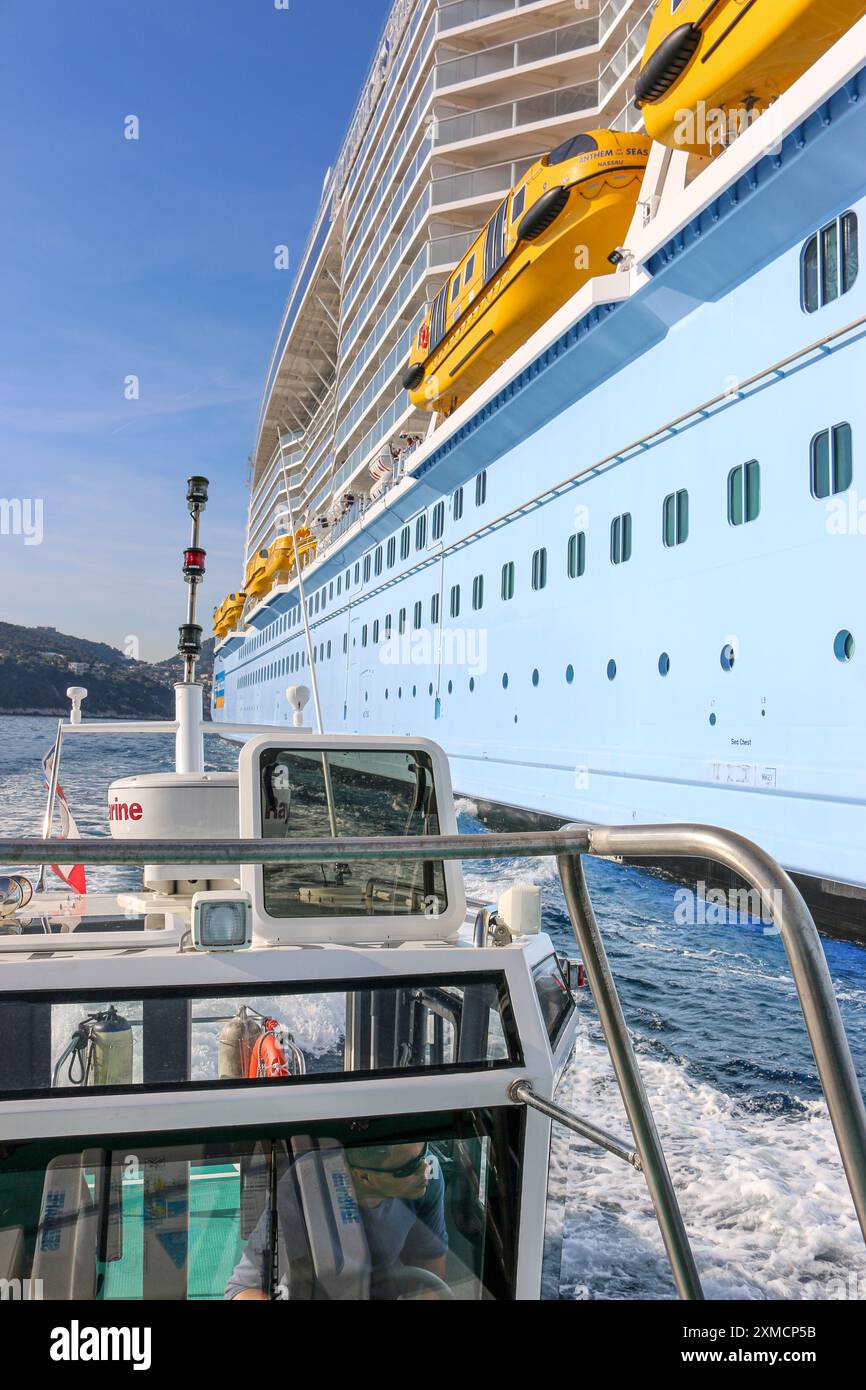 Nizza, Frankreich: Hafenpilotenboot nähert sich der riesigen MEERESHYMNE der Royal Caribbean, um in Villefranche sur Mer von Bord zu gehen. Ein einzigartiger Zwischenstopp für das größte Kreuzfahrtschiff dieses Jahr im kleinen Hafen der französischen Riviera. Nach der Sommersaison sollte das beeindruckende Schiff im Rahmen einer Umschichtung von Europa nach Singapur durch den Suez-Kanal segeln, aber nach Spannungen am Roten Meer und Drohungen mit Houthi-Raketen auf Schiffe, stattdessen wird sie ohne Passagier die Südspitze Afrikas erkunden, um Dubai und Asien zu erreichen. Quelle: Kevin Izorce/Alamy Live News Stockfoto