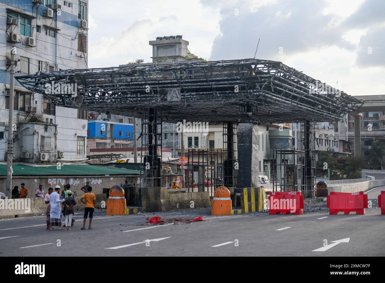 Dhaka, Bangladesch. Juli 2024. Die Menschen schauen auf die toll plaza der erhöhten Schnellstraße, die von einem Mob während der Auseinandersetzungen nach Studentenprotesten gegen staatliche Jobquoten in Brand gesetzt wurde. (Foto: Piyas Biswas/SOPA Images/SIPA USA) Credit: SIPA USA/Alamy Live News Stockfoto