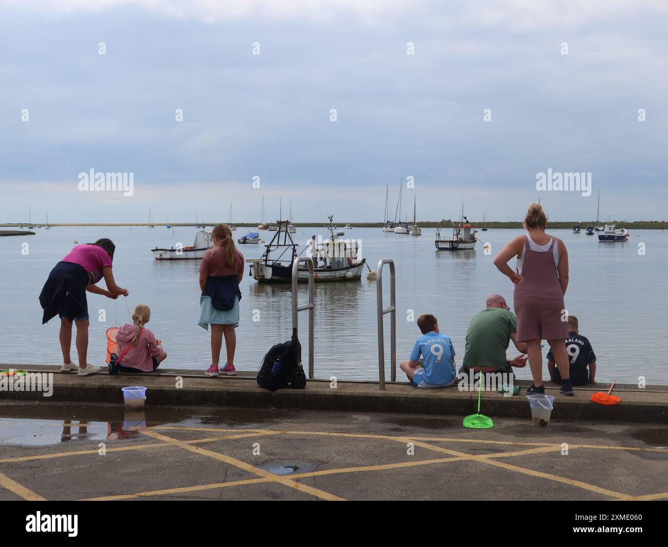 Sommerferien in Suffolk: Familien mit Kindern säumen entlang der Küste von Orford mit ihren Fischernetzen und Eimern, um Krabben zu fangen. Stockfoto