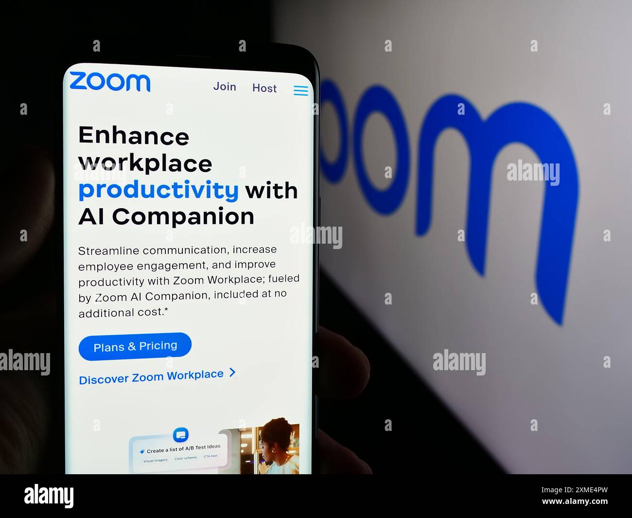 Person, die ein Mobiltelefon hält, mit Webseite des US-amerikanischen Kommunikationsunternehmens Zoom Video Communications Inc. Mit Logo. Konzentrieren Sie sich auf die Mitte des Telefondisplays. Stockfoto