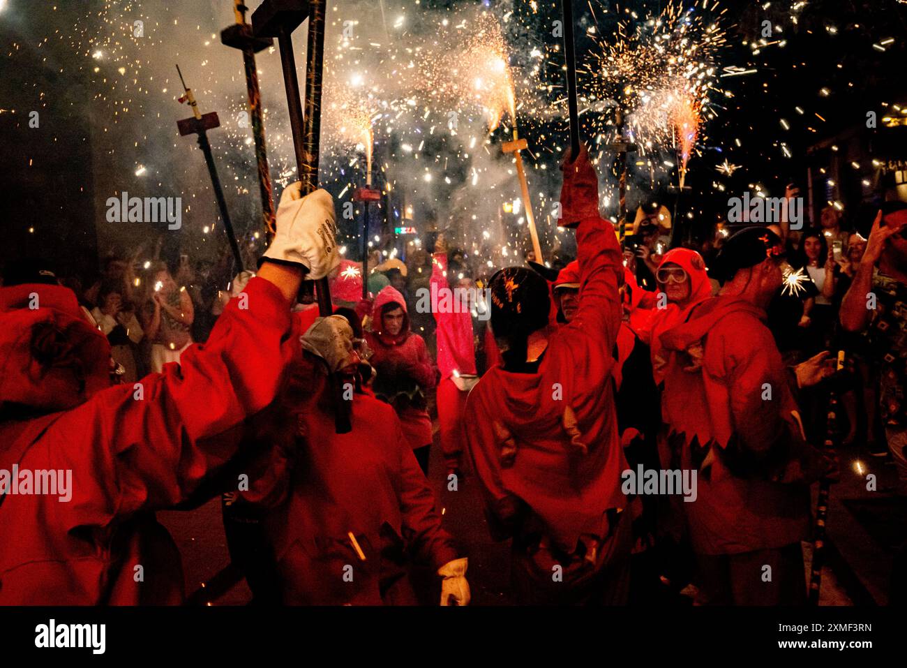 Barcelona, Spanien. 27. Juli 2024, Barcelona, Spanien - Menschen, die als Teufel gekleidet sind, machen während eines Korrefoc anlässlich des Sommerfestes im Poble SEC-Viertel in Barcelona explodierende Pyrotechniken. Correfocs sind eine alte katalanische Tradition, in der sich die Menschen als Teufel kleiden und Feuerwerkskörper und Fackeln anfeuern. Quelle: Jordi Boixareu/Alamy Life News Stockfoto