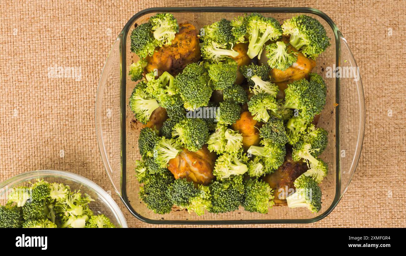 Gebackene Hähnchenkeulen und Brokkoli-Rezept. Backform in Nahaufnahme auf einem Küchentisch, flach Stockfoto