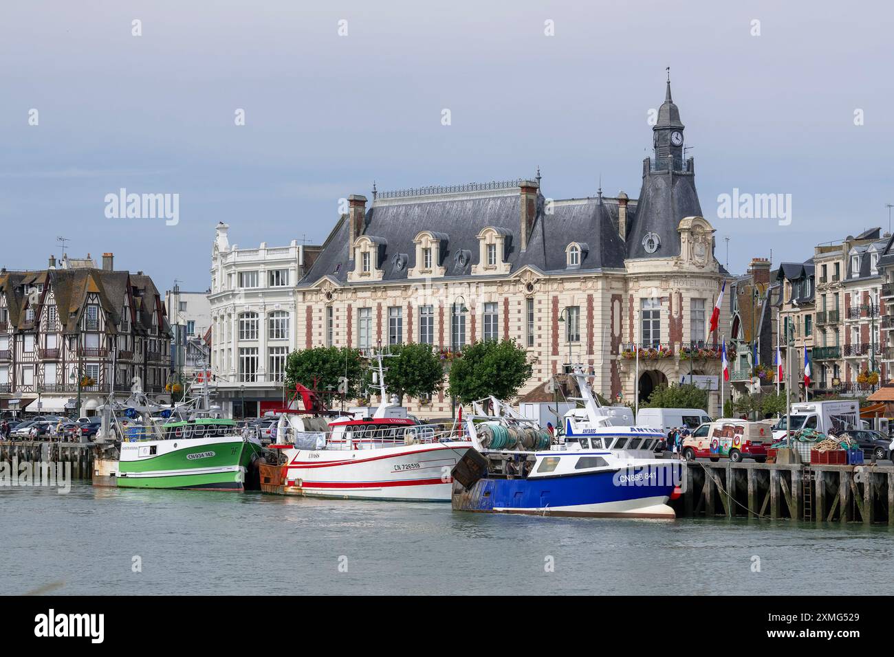 Trouville-sur-Mer, Frankreich - Blick auf den Kai des Flusses Touques mit Fischerbooten und das Rathaus in der Innenstadt von Trouville. Stockfoto