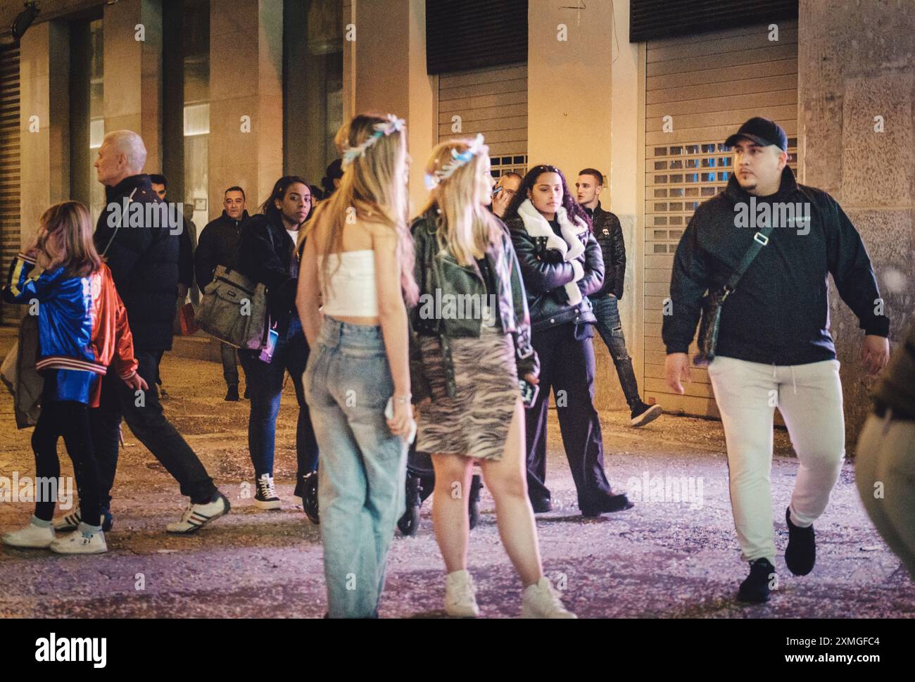 Gruppe von Menschen, die nachts auf einer Straße in der Stadt gesellig sind und ein offenes urbanes Nachtleben in lässigen Outfits darstellen. Stockfoto