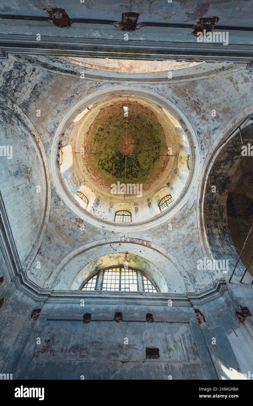 Innenansicht einer verlassenen Kirche mit Schwerpunkt auf der sich verschlechternden Kuppel mit abblätternder Farbe und freiliegenden Ziegeln, die das Alte und die Weite des Gebäudes einfangen Stockfoto
