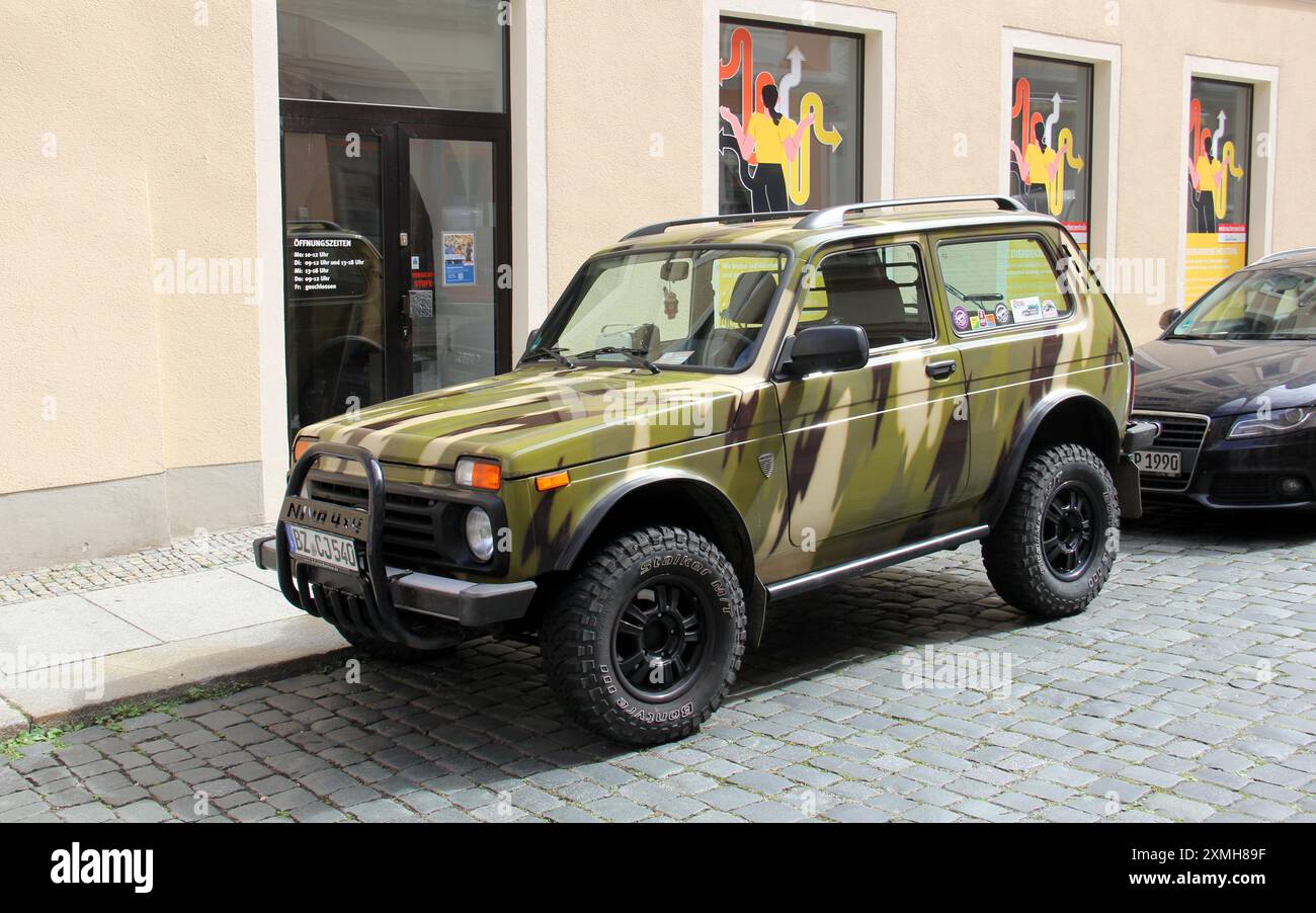 Lada Niva Bronto Geländewagen, gemalt in Tarnfarben, parkt an einem Bürgersteig auf einer Kopfsteinpflasterstraße, Bautzen, Deutschland Stockfoto
