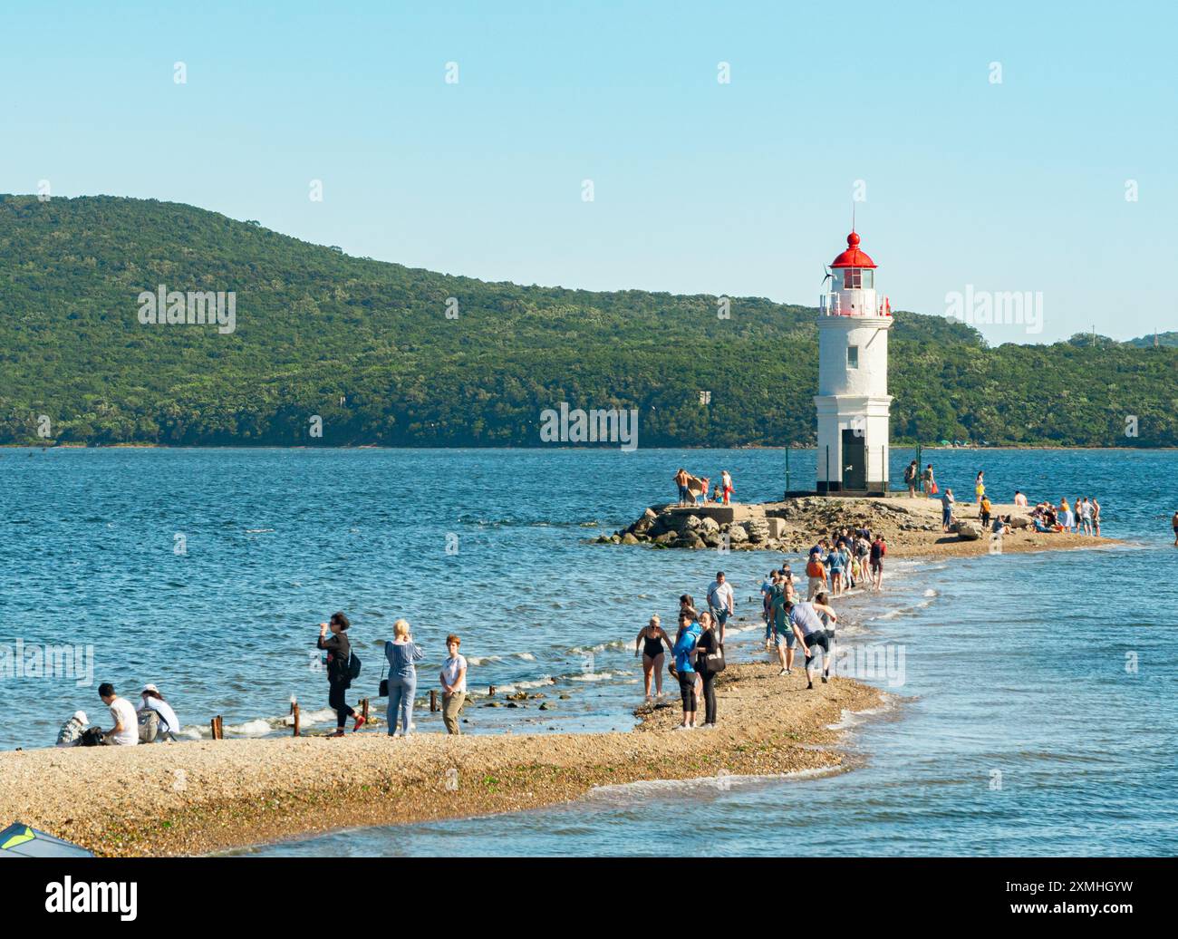 Wladiwostok, Russland - 1. September 2018: Blick auf Menschen, die bei Sonnenuntergang an der Nehrung zum Tokarewski-Leuchtturm gehen. Stockfoto