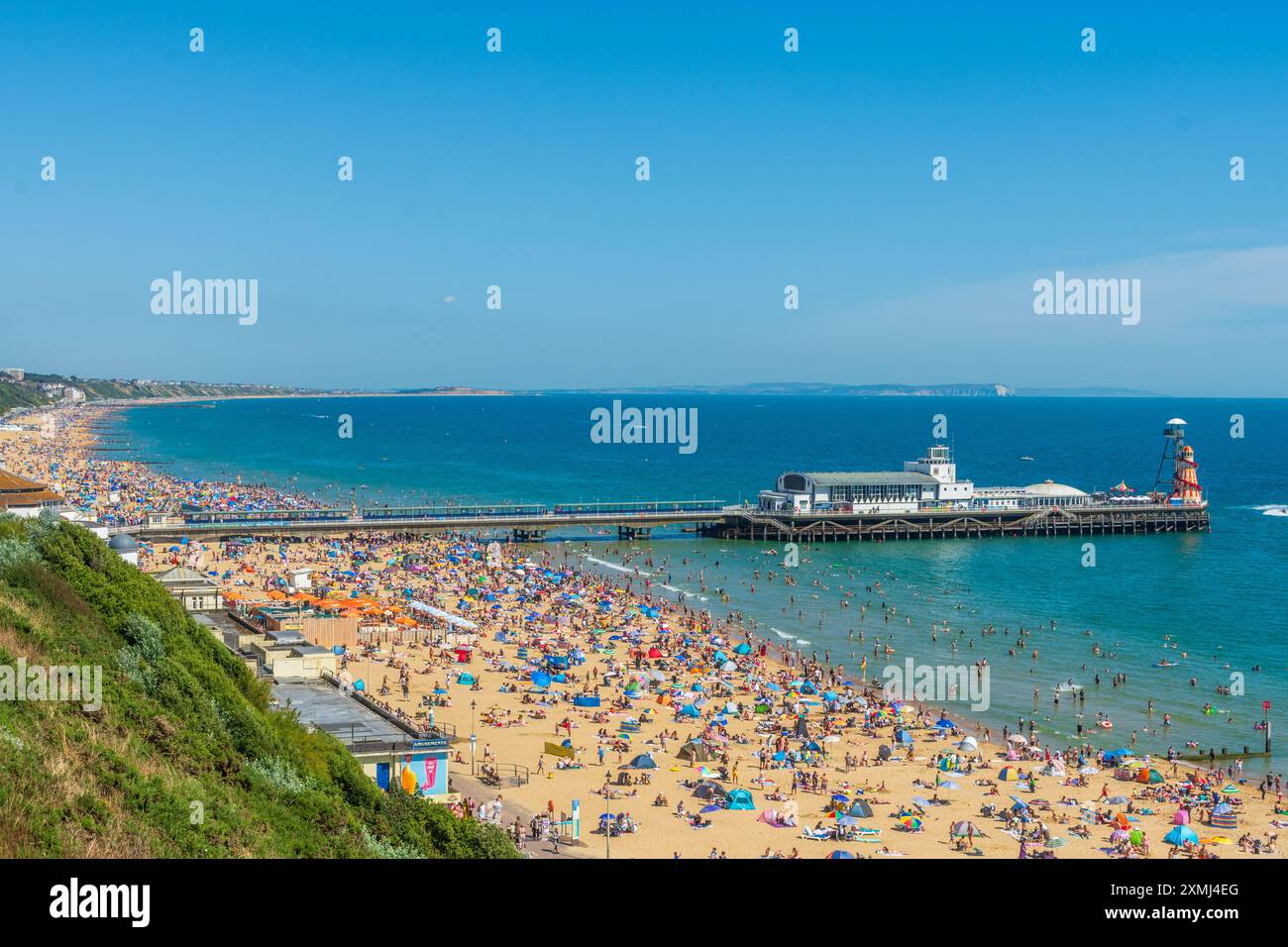 West Cliff Beach, Bournemouth, Großbritannien - 28. Juli 2024: Blick von der Klippe des Bournemouth Pier und den überfüllten Strand von Menschen, die das heiße Wetter genießen. Stockfoto
