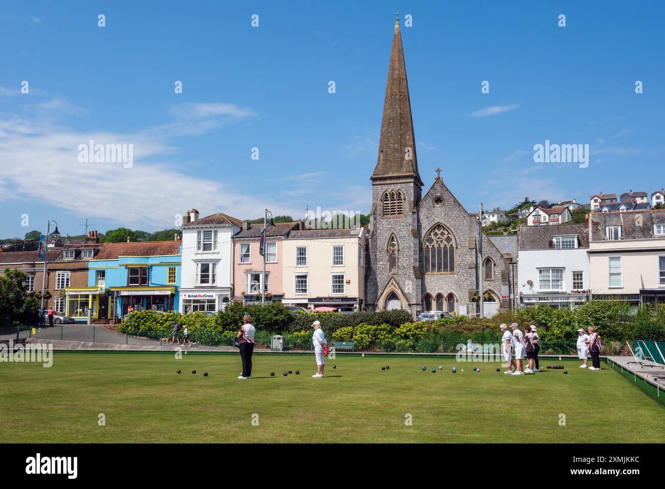 Frauen spielen Bowling im Dawlish Bowling Club (Blick auf Strand und Dawlish United Reform Church), Dawlish, Devon Stockfoto