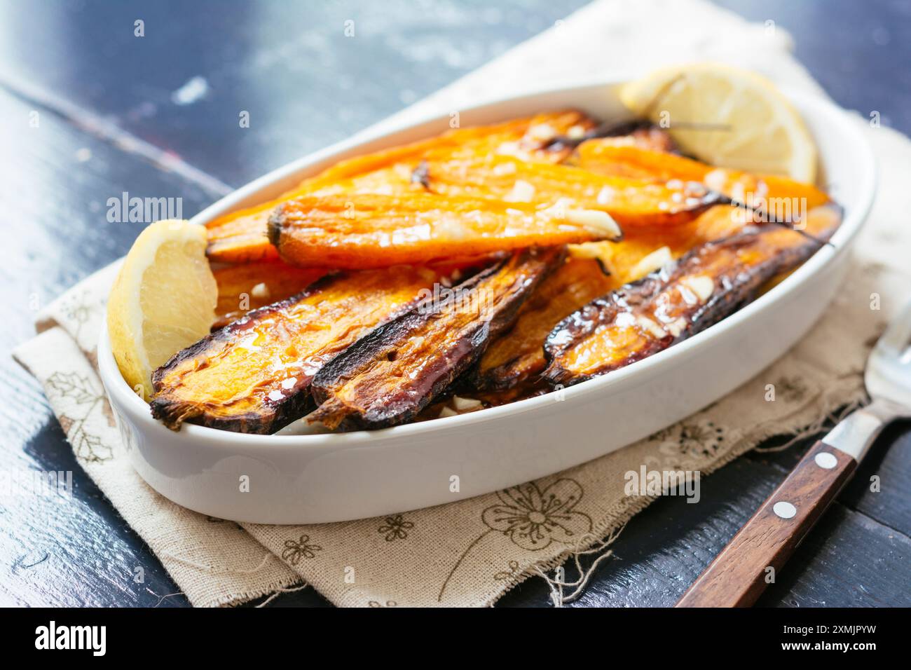 Hausgemachte Beilage mit gebackenem lila und normalen Karotten mit Knoblauch und Limette. Stockfoto