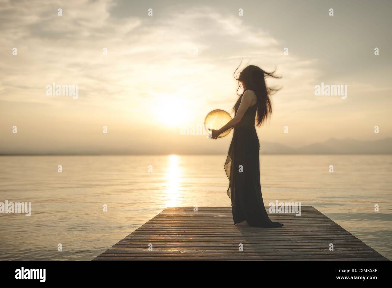 Frau in Bewegung, die eine surreale Kugel umarmt, die von der Sonne beleuchtet wird, die Energie freisetzt, abstraktes Konzept Stockfoto