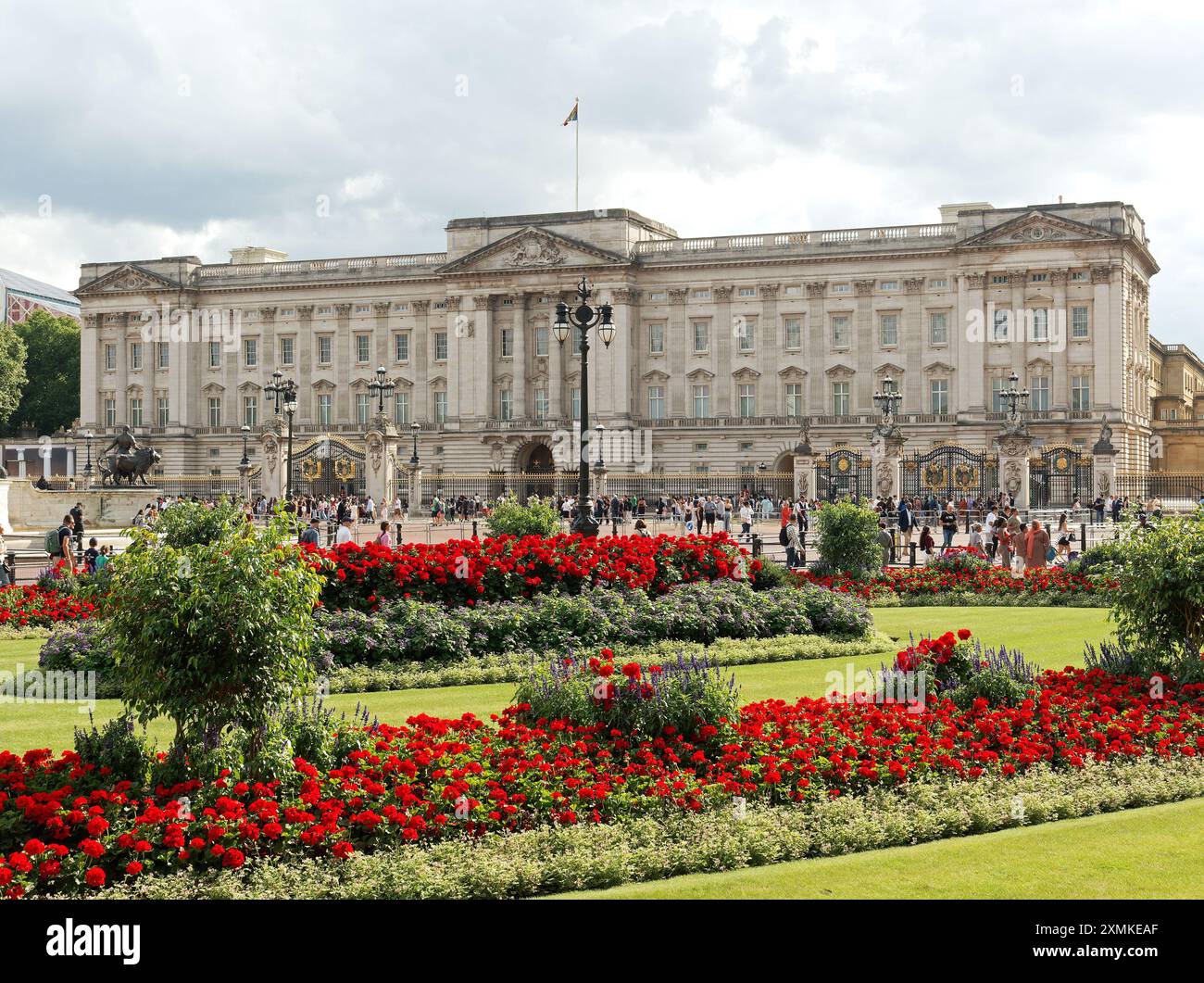 Blick auf den belebten Buckingham Palace in London mit den bunten Blumen des Constitution Hill Memorial Garden im Vordergrund Stockfoto