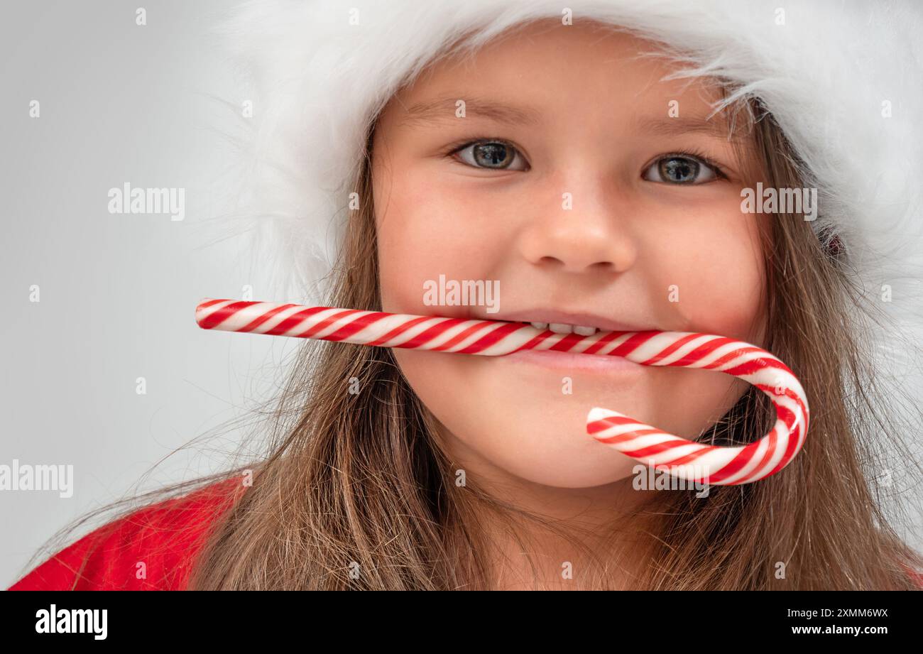 Weihnachtsporträt eines Kindes auf Weihnachtsmütze mit Zuckerrohr Stockfoto