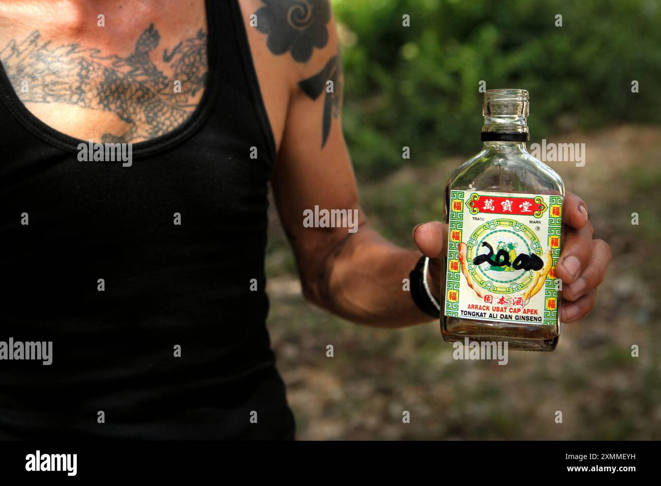 Ein Mann, der eine Flasche eines Energy Drinks aus Malaysia während einer Ökotourismus-Veranstaltung im Langhaus der traditionellen Dayak IBAN-Gemeinde in Sungai Utik, Batu Lintang, Embaloh Hulu, Kapuas Hulu, West Kalimantan zeigt. Indonesien. Bis 2012 sind einige der malaysischen Produkte leicht im indonesischen Distrikt Embaloh Hulu im Regierungsbezirk Kapuas Hulu in der Provinz West Kalimantan zu finden. Die indonesische Seite der Grenze zu Malaysia, der Grenzposten Nanga Badau, wurde 2017 von Präsident Joko Widodo offiziell eingeweiht. Stockfoto